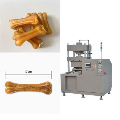 Cão que mastiga o osso de cão dos petiscos que faz a máquina, equipamento de processamento dos alimentos para animais de estimação